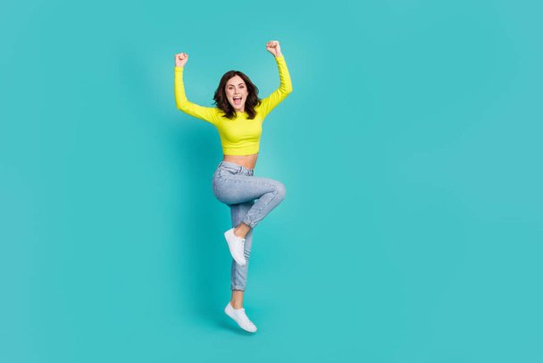 Full size photo of astonished girl jump raise fists success achieve isolated on cyan color background. - Photo, Image