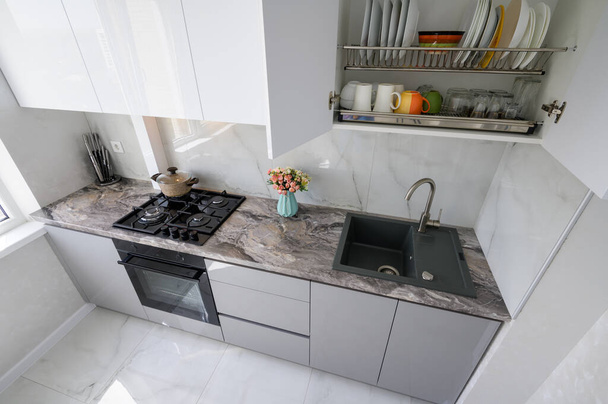 Высокий угол зрения на белую компактную современную домашнюю кухонную мебель после ремонта - Фото, изображение
