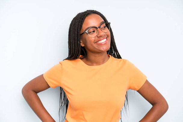 black young adult woman looking happy, cheerful and confident, smiling proudly and looking to side with both hands on hips - 写真・画像