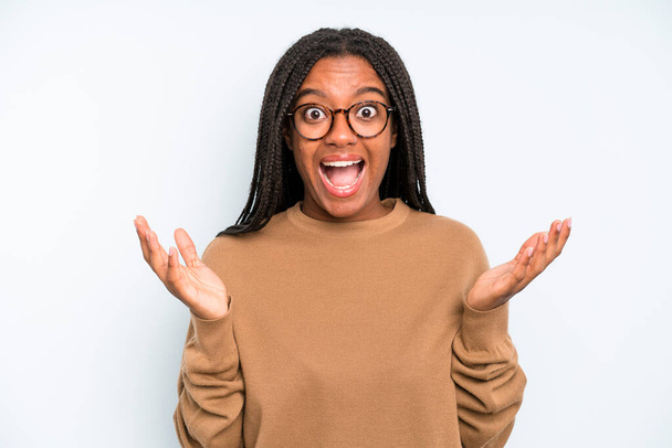 black young adult woman looking happy and excited, shocked with an unexpected surprise with both hands open next to face - Foto, Bild