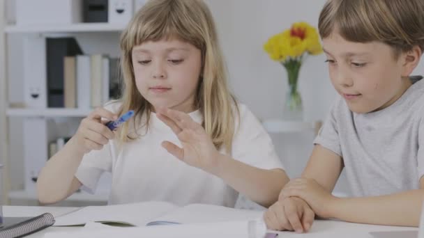 Boy of 9 years old helps his younger sister to make her homework. High quality 4k footage - Materiaali, video