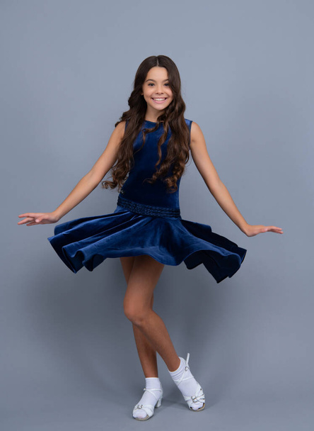 Teenager portrait with movement dress. Young teen child with flowing skirt. Teen girl fluttering dress in motion, isolated on gray. Positive and smiling emotions - Foto, imagen