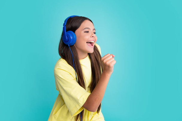 Child music concept. Teenager child girl dances in rhythm of melody, listens song in headphones. Child listening to music through earphones. Excited face, cheerful emotions of teenager girl - Fotó, kép