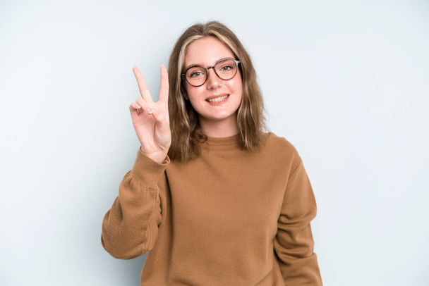caucasian pretty woman smiling and looking happy, carefree and positive, gesturing victory or peace with one hand - Foto, Bild