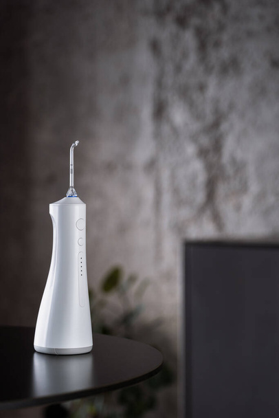 closeup of portable irrigator for dental health and teeth protection on dark table at home background - Foto, afbeelding