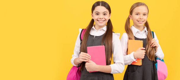 School girls friends. Happy kids in fomal uniforms with study books carry school bags. Portrait of schoolgirl student, banner header. School child face isolated panorama background with copy space - Photo, Image