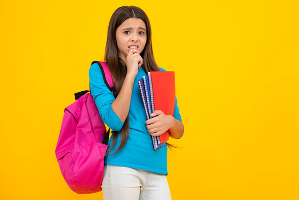 Schoolchild, teenage student girl hold book on yellow isolated studio background. School and education concept. Back to school. Angry face, upset emotions of teenager girl - Φωτογραφία, εικόνα