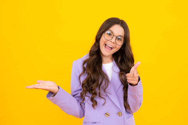 Amazed teen girl. Positive teenager child points aside with cheerful expression, shows amazing at blank empty space. Advertisement and mockup. Excited expression, cheerful and glad - Valokuva, kuva
