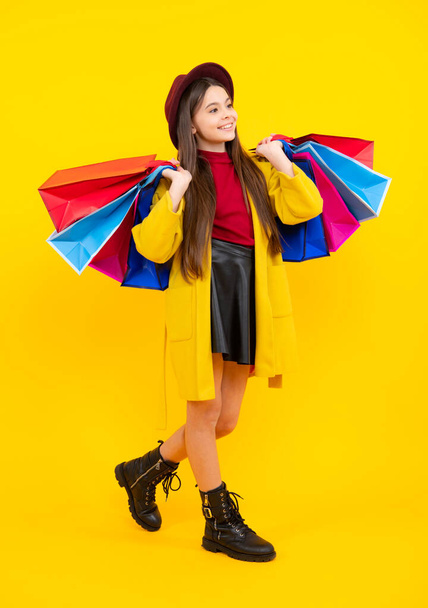 Happy teenager portrait. Funny teen girl hold shopping bag enjoying sale isolated on yellow. Portrait of teenager schoolgirl is ready to go shopping. Smiling girl - Foto, Imagem