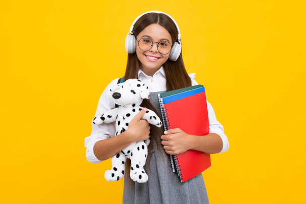 Funny school girl with toy isolated on yellow background. Happy childhood and kids education. Happy schoolgirl, positive and smiling emotions - Foto, Imagem