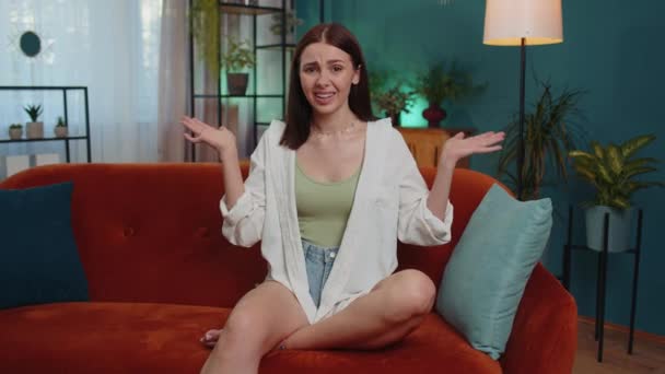 What. Why. Lovely girl raising hands in indignant expression, asking reason of failure, demonstrating disbelief irritation by troubles at home apartment. Young woman in room sitting on orange sofa - Séquence, vidéo