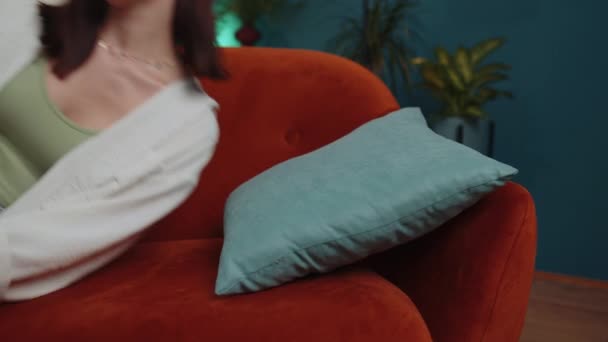 Tired caucasian adult girl lying down in bed taking a rest at home. Carefree young woman napping, falling asleep on comfortable orange sofa with pillows. Closed her eyes enjoy daytime nap alone - Video