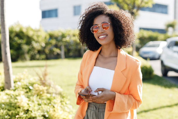 smiling Afro American woman with phone outdoors. High quality photo - Valokuva, kuva
