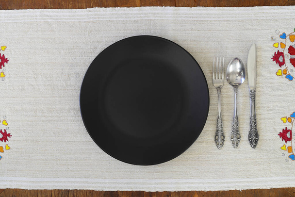 Empty black slate plate on wooden table. Food background for menu, recipe. Table setting. Flatlay, top view. Mockup for restaurant dish - Zdjęcie, obraz