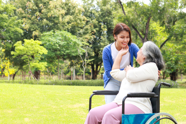 A caregiver shakes hands of an elderly person sitting on a wheelchair. Nursing concepts to take care of elderly health care, senior health rehabilitation center. child taking care of old mother. - 写真・画像