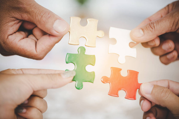 Hands holding piece of blank jigsaw puzzle for teamwork workplace success and strategy concept. - Foto, Imagem