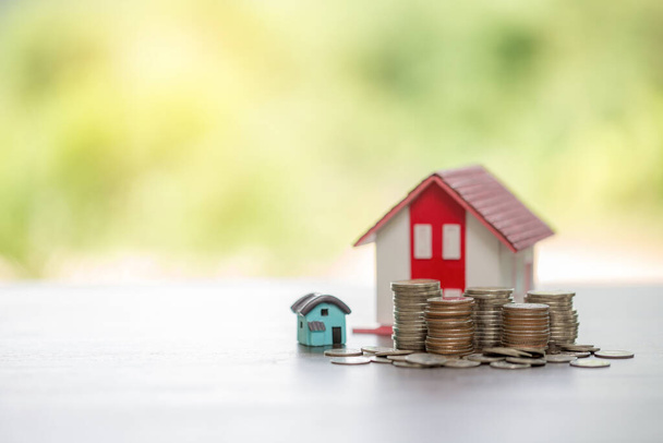 House model and money coins stacks with blur nature background. Savings plans for home, loan, investment, mortgage, finance and banking about house concept. - 写真・画像