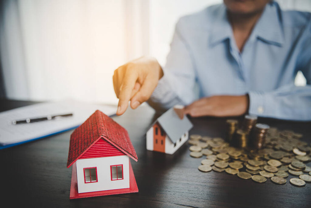 House model with stack coins, business hand is planning savings money of coins for buy home. concept for property ladder, mortgage with real estate investment and saving or investment for a house - 写真・画像
