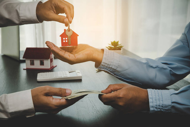 real estate agent holding house key to his client after signing contract, concept for business loan, investment mortgage, real estate, moving home or renting property. - Foto, Imagen