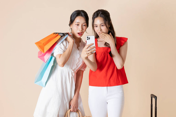 giovani donne coreane che navigano smartphone e tenendo borse della spesa  - Foto, immagini