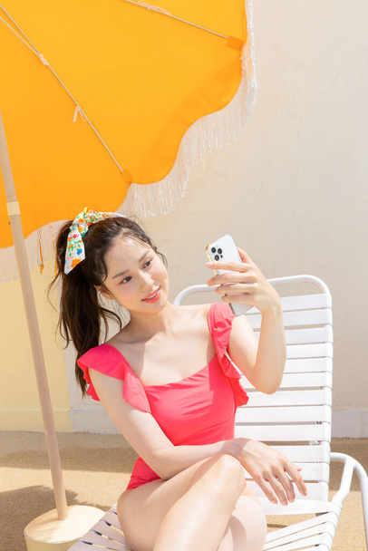 vacaciones de verano concept _ korean hermosa asiática joven mujer tomando un selfie sentado en el sunbed - Foto, imagen