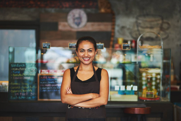 Shes the queen of coffee. Portrait of a young barista posing with her arms crossed in a coffee shot - Foto, Imagen