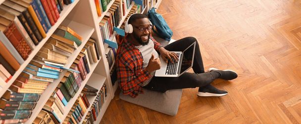 African-American student with laptop preparing for exam in library - Фото, изображение