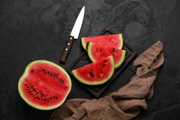 Cutting board of tasty watermelon, knife and napkin on dark background - Foto, Imagem