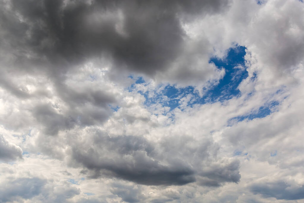 Fragment of the sky almost completely covered with cumulus and storm clouds - 写真・画像