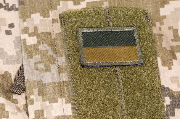 Текстиль украинского флага наклейка в камуфляжной серо-коричневой цветовой гамме на оливковой основе с крючком и петлей крепится на военной камуфляжной униформе - Фото, изображение