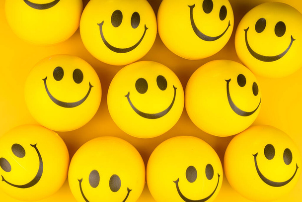 Ευτυχισμένα πρόσωπα μπάλα σε κίτρινο φόντο, χαμογελαστό φόντο. - Φωτογραφία, εικόνα
