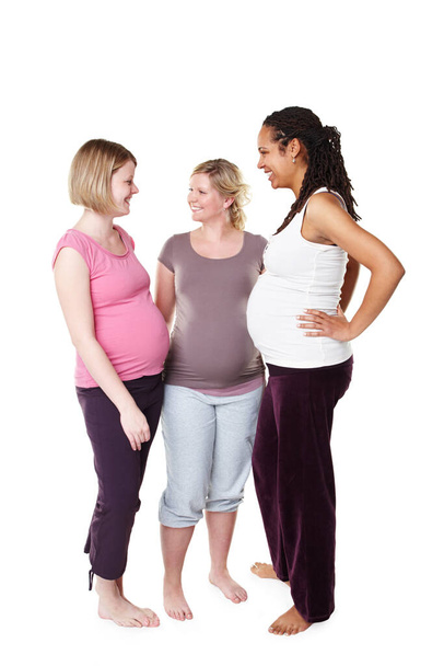 Happy pregnant friends talking in white background studio with pilates, health or yoga clothes. Mother, maternity and communication with women having a pregnancy lifestyle discussion together. - Foto, imagen