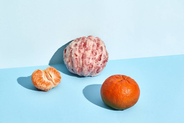 Mandarin and a half of grapefruit on lifht blue backgraund - Fotografie, Obrázek