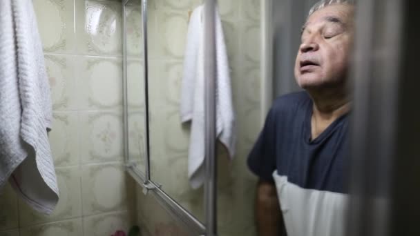 Беспокоится, что пожилой мужчина вздыхает в зеркало ванной, страдая от кризиса среднего возраста - Кадры, видео