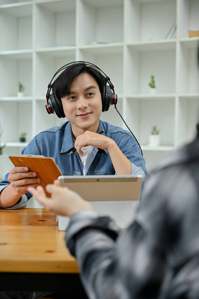 Портрет, молодой азиатский радиоведущий, берёт интервью у своего специального гостя в студии. Концепция вещания и подкастинга - Фото, изображение
