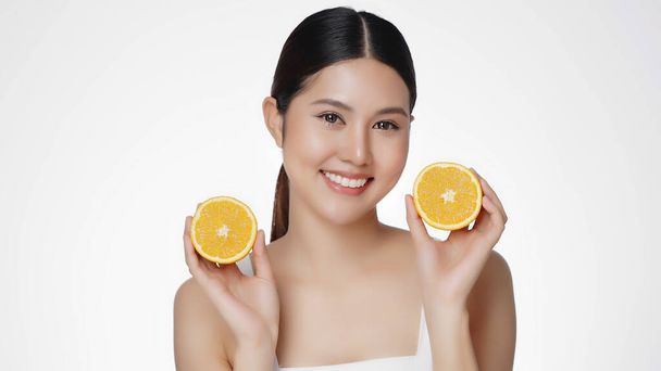 Asian woman are happy with perfect clean healthy skin. Cute female model clean fresh skin is holding an orange. Expressive facial expressions. Cosmetology. - Photo, Image