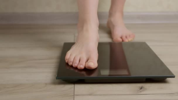 Feet of a woman standing on the scales for weighing. - Video