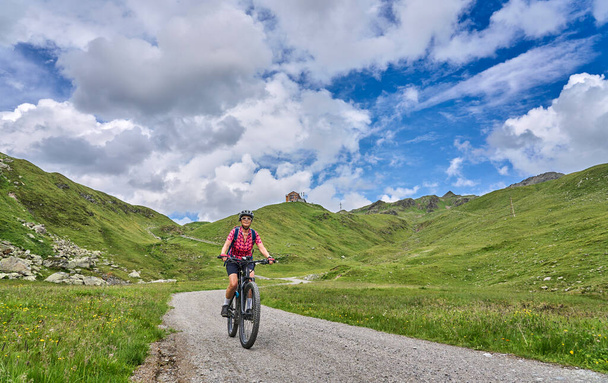 nice active senior woman riding her electric mountain bike in the silvretta mountain range near Gaschurn, Tyrol, Austria - Fotoğraf, Görsel