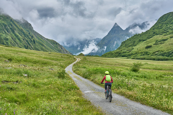 nice active senior woman riding her electric mountain bike in the silvretta mountain range near Gaschurn, Tyrol, Austria - Photo, Image