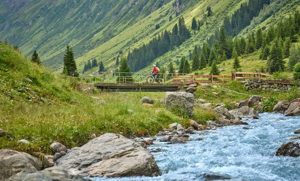 nice active senior woman riding her electric mountain bike in the Jamtal Valley, silvretta mountain range near Gaschurn, Tyrol, Austria - Fotografie, Obrázek