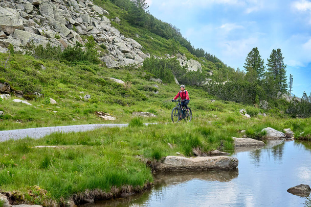 nice active senior woman riding her electric mountain bike in the silvretta mountain range near Gaschurn, Tyrol, Austria - Fotó, kép