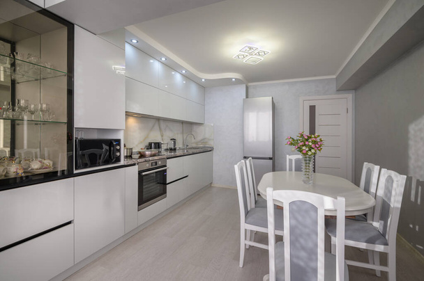 Interior of well designed modern trendy white kitchen with dining table, corner view - Foto, Imagen