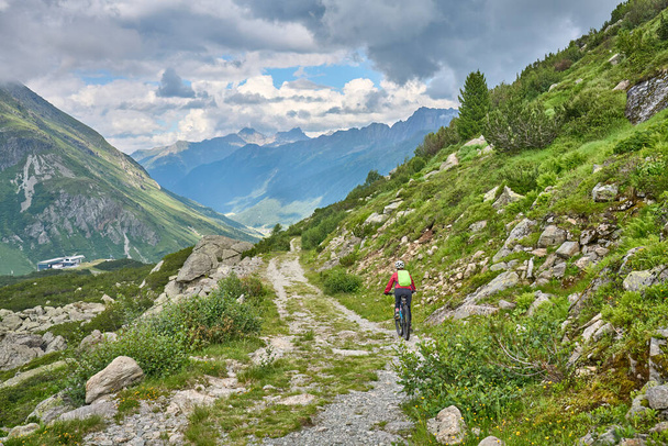 nice active senior woman riding her electric mountain bike in the silvretta mountain range near Gaschurn, Tyrol, Austria - Photo, Image