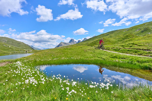 nice active senior woman riding her electric mountain bike in the silvretta mountain range near Gaschurn, Tyrol, Austria - 写真・画像