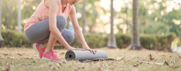 Young Asian woman with yoga mat for practice yoga in park outdoor. Female healthy go out to outdoor activities. - Foto, Imagem