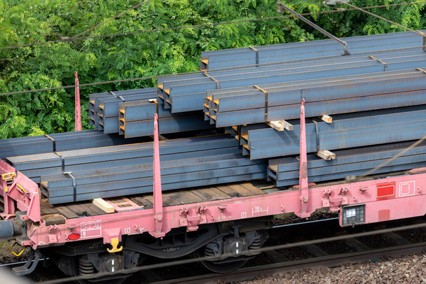 Heap pile heavy raw rusted steel iron beam girders loaded on railroad cargo freight carriage. Metal goods factory plant products shipping and logistics. Metallurgy industrial transportation service. - Fotografie, Obrázek