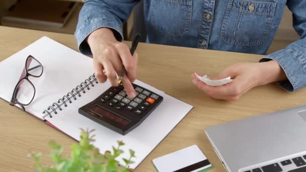 A young woman checks bills, a cash receipt for purchases and calculates budget expenses. Family finance concept. - Video, Çekim