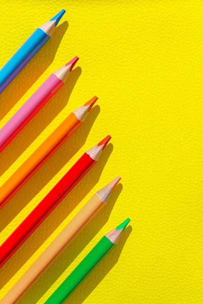 Colorful wooden pencils on bright yellow background. Minimal style composition. Top view. Flat lay. Back to school concept - 写真・画像