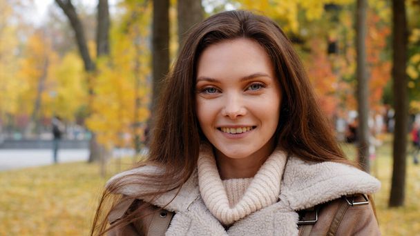Female portrait attractive beautiful caucasian woman girlfriend lady stand alone in autumn urban park rejoice laugh feeling joy flirting smiling healthy white smile looking at camera posing outdoors - Photo, image