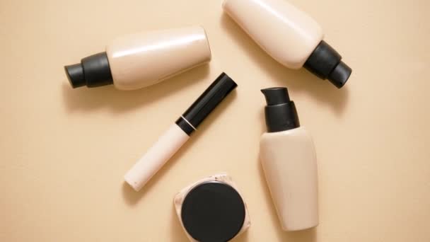 Flessen make-up foundation en samples op beige achtergrond. Vlakke lay, bovenaanzicht - Video